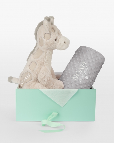 Kosedyr og grått teppe med brodert navn og dato