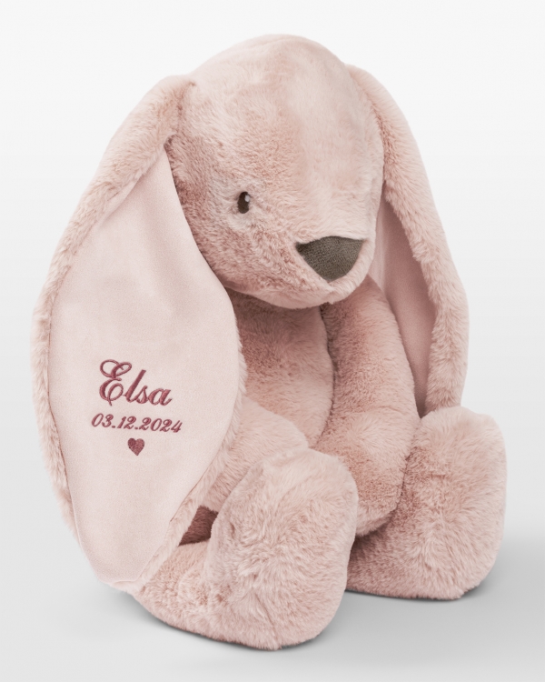 Stor kosekanin med rosa broderi av navn og fødselsdato.