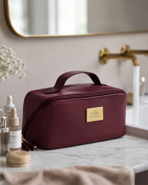 Romslig toalettmappe i vinrødt med gravert navn og gulldetaljer