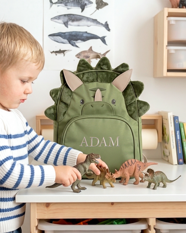 Barnesekk formet som en dinosaur, med brodert navn og blå matboks og vannflaske