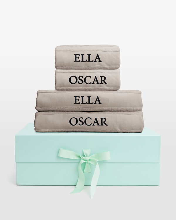 Sandfarget håndklærsett med dusjhåndklær og svart navnebrodert design, perfekt for moderne komfort og subtil eleganse.