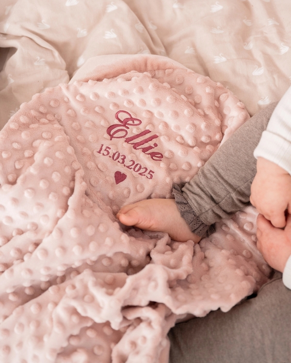 Rosa mykt teppe med brodert navn og fødselsdato.