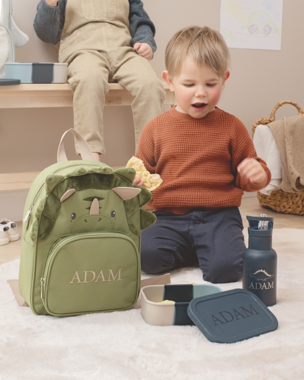 grønn ryggsekk formet som en dinosaur